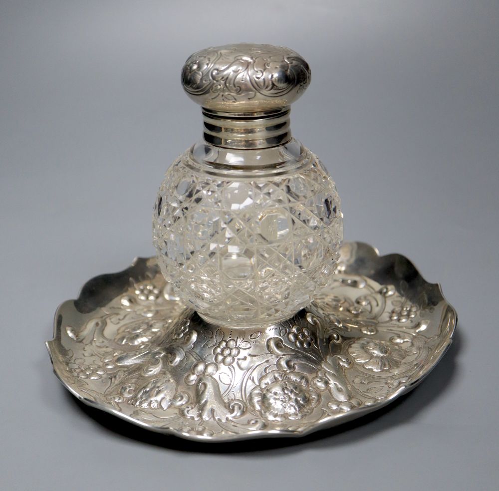 A late Victorian repousse silver mounted glass inkwell, on a repousse silver stand, London, 1891, height 14.4cm.